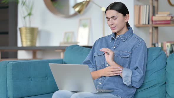 Latin Woman with Laptop Having Wrist Pain on Sofa 