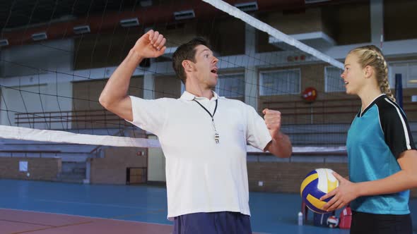 Male coach assisting volleyball player