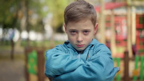 Closeup Portrait of Sad Caucasian Boy with Red Eyes Looking at Camera Crossing Hands