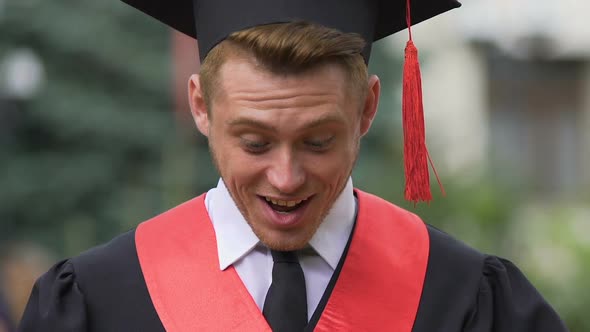 Surprised Male Graduate Looking Down With Smile on Face, Career Opportunity