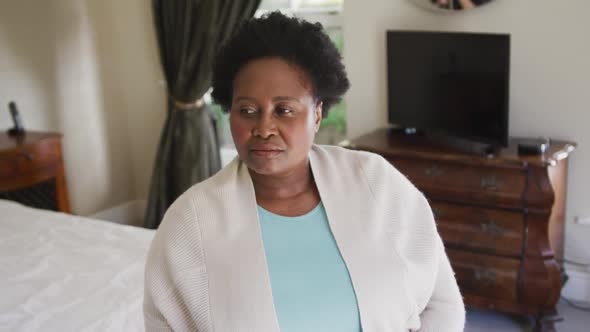 Thoughtful african american senior woman sitting on the bed at home