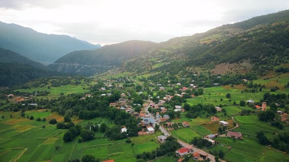 Aerial drone view of a village in Georgia. Valley, buildings, mountains and hills slopes covered wit