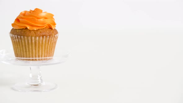 Cupcake with Orange Frosting on Glass Stand