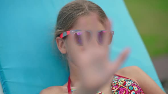 Closeup Portrait of Happy Caucasian Girl in Sunglasses Sending Air Kiss in Slow Motion Smiling Lying