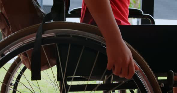 Side view of disabled African American schoolboy moving his wheelchair in school corridor 4k