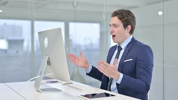 Attractive Young Businessman Celebrating Success on Desk Top