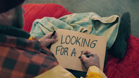 A Beggar is Writing 'Looking for a Job' on a Plate