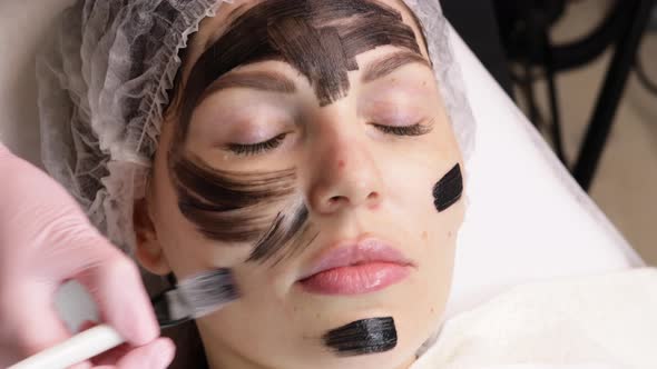 Beautician Applies Black Mask on Face of Beautiful Woman