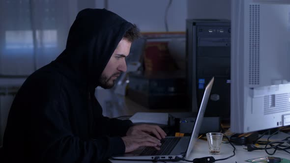 Hacker typing on computer in the dark - cyber crime