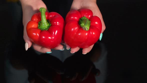 Closeup of Woman Holding Ripe Red Pepper on Black Background