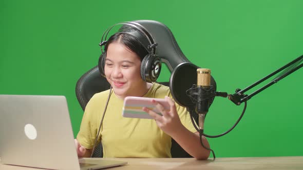 Asian Kid Girl Hold Mobile Phone And Read Comment In Laptop Then Talking To Camera While Live Stream