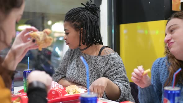 young women multiethnic indoor eating at fast food