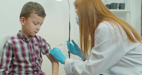A Doctor Injects a Vaccine Into the Boy Shoulder
