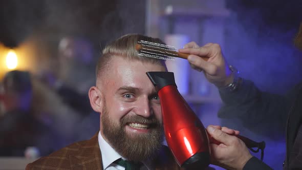 Crazy Stylish Man Sitting in Barber Shop While Hairdresser Dry His Hair.