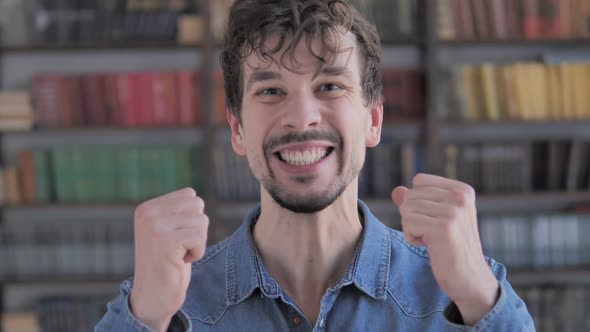 Casual Young Man Celebrating Success Gesture in Office