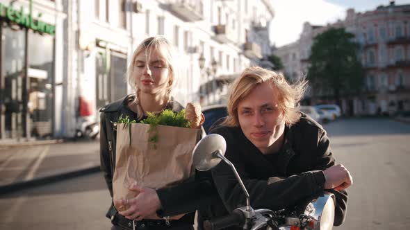 Portrait of Happy Cheerful Young Hipster Couple Sitting on a Vintage Scooter in Old City Center with