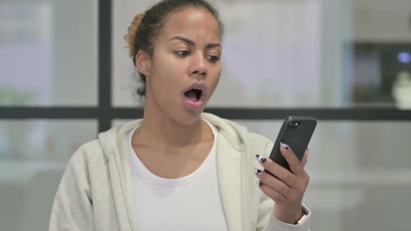 Portrait of African Woman Reacting to Loss on Smartphone
