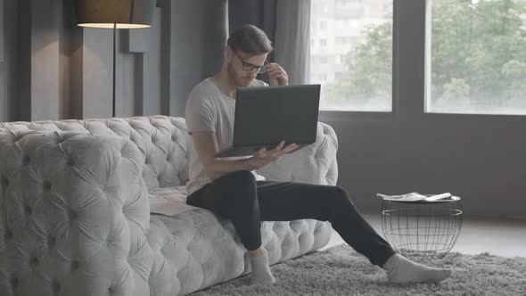 Wide Shot Portrait of Busy Caucasian Businessman Comparing Online Information in Documents