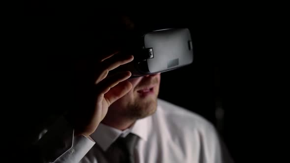 Business Man in Shirt and Tie Plays with Virtual Reality Glasses in Dark Room