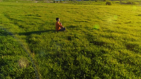 Low Altitude Radial Flight Over Sport Yoga Man at Perfect Green Grass. Sunset in Mountain