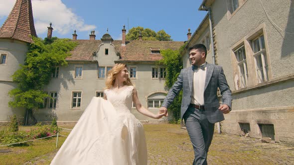 Moldovan Couple Running in Slow Motion Holding Hands on a Sunny Day. The Newlyweds Smile and Look