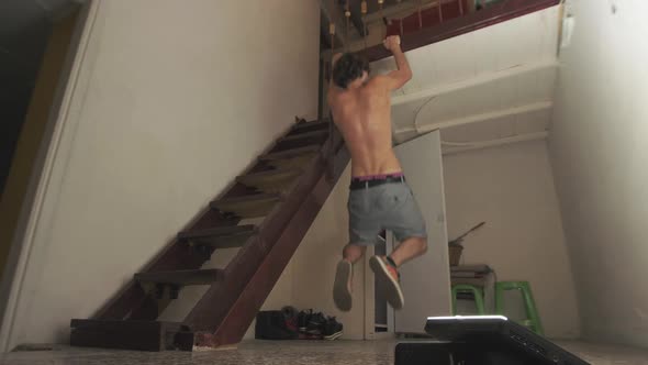 Young man bodyweight workout inside home doing pull ups