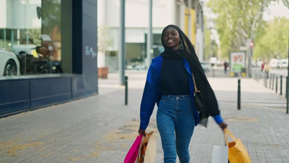 Happy Black Shopaholic in Hijab Walking on Street