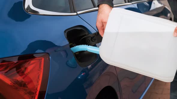 Close Up Man Filling a Diesel Engine or Exhaust Fluid DEF From Canister Into the Tank of Blue Car.