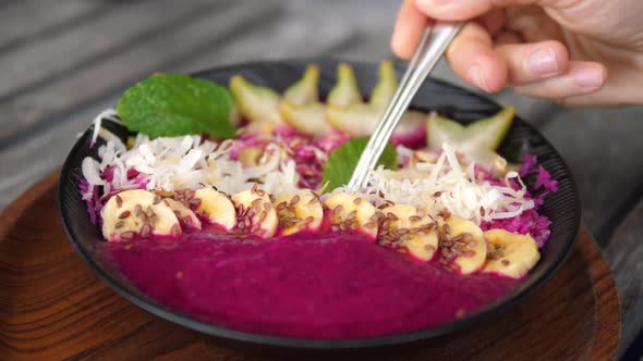 Spoon Dips Into Dragon Fruit Smoothie Bowl Showing It to the Camera