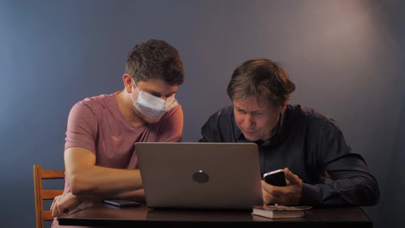 Son with Mask Explains How Work with Laptop To Senior Father