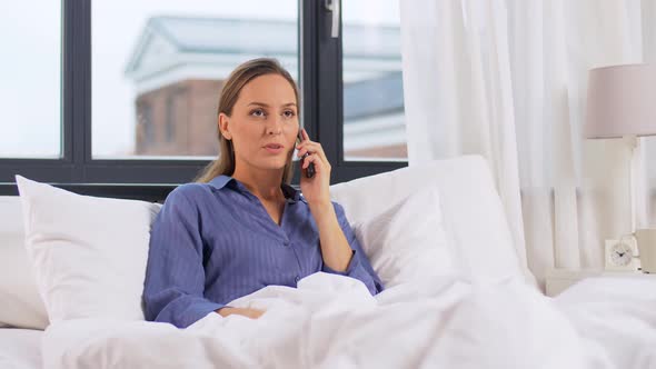 Young Woman Calling on Smartphone in Bed at Home