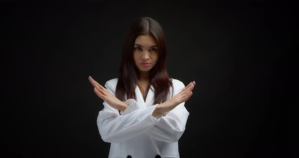 Angry Young Woman Holds Her Crossed Arms in an x Gesture and Looks at the Camera