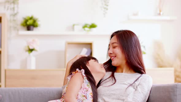 Close up of a proud mother watching her baby snuggling on her chest while their both sitting at a so