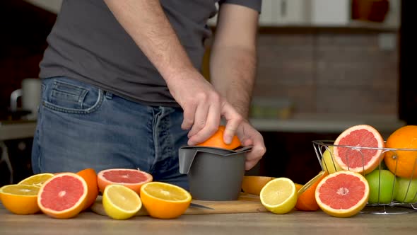 A Man is Squeezes Orange Juice with Citrus Juicer