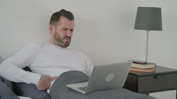 Man with Back Pain Working on Laptop in Bed