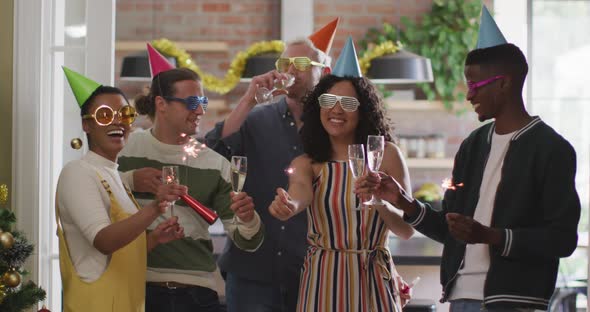 Happy group of diverse friends in party hats celebrating together, toasting with vine