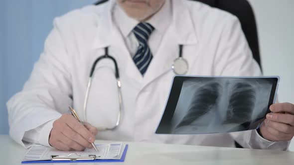 Pulmonologist Looking at X-Ray of Lungs and Prescribing Treatment to Patient