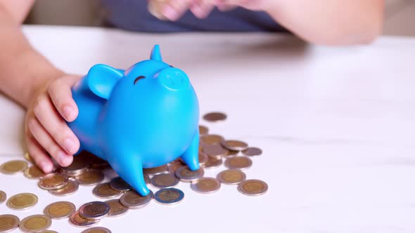 Piggy Bank saving business standing on a pile of coins concept. A hand is putting a coin in a piggy