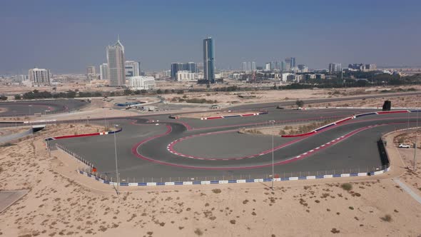 Aerial view of empty Dubai Autodrome race track hairpin turn, Dubai skyline