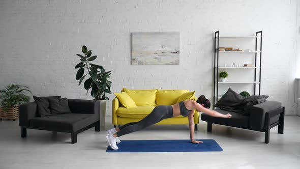 Beautiful Young Woman Does Exercises for the Abdomen on the Rug in the Room