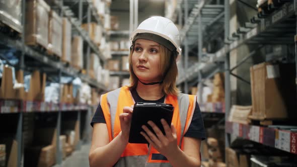 Professional Worker Wearing Hard Hat and Uniform Uses Digital Gadget Checks Inventory Walks in the