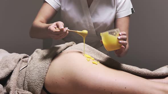 Woman in spa salon having anti cellulite massage therapy with honey for fat burning.