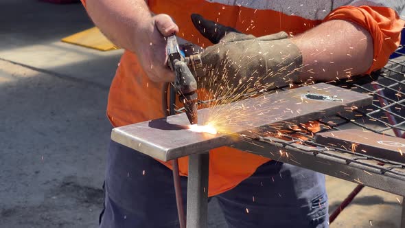 Gas welder being used to blow a hole into a sheet of steel