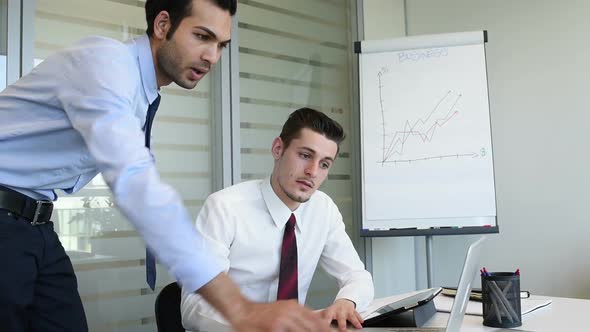 two young business man indoor office interior using personal computer discussing