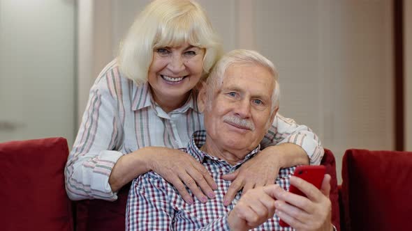 Senior Grandparents Couple Talking and Using Digital Mobile Phone at Home. Coronavirus Lockdown