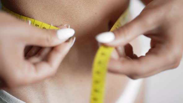 A Girl is Measuring Her Waist with a Centimeter Tape