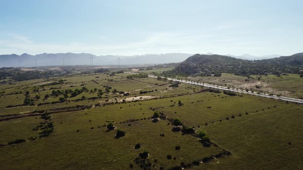 Landscape around Ninh Chu, road and wind turbines in background. Aerial forward