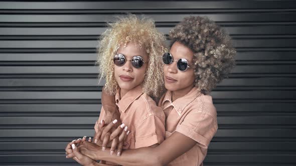 Portrait of Young Black Twins Sisters with Blond Hair and Sunglasses Smiling and Embracing Each