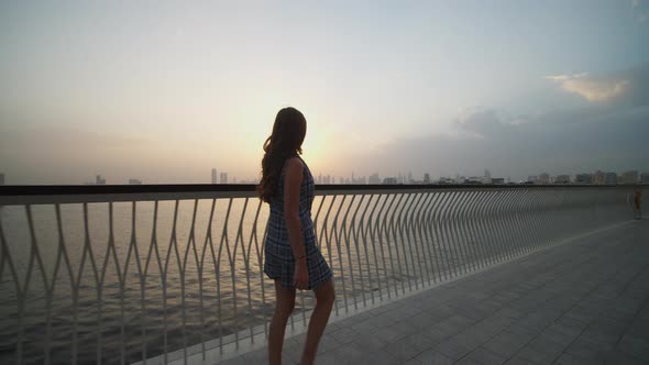 Woman Walking By the Sea with Dubai Skyline in the Background