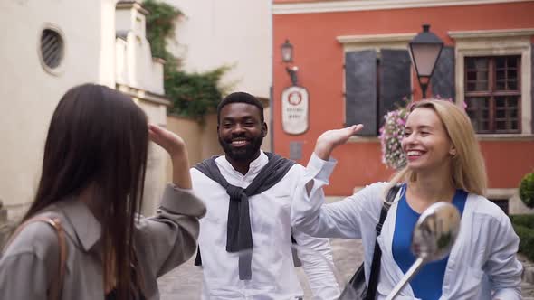 Likable Cheerful Young Friends Giving high Five Each Other in the Urban Yard